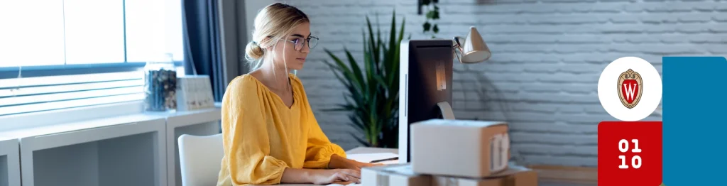 “A person in a yellow top working on a computer in a professional workspace, with a lamp and calendar